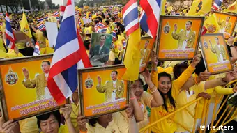 People hold pictures of Thailand's King Bhumibol Adulyadej as they wait for him to arrive at the Anantasamakom Throne Hall in Bangkok December 5, 2012. King Bhumibol celebrates his 85th birthday on Wednesday. REUTERS/Sukree Sukplang (THAILAND - Tags: POLITICS ANNIVERSARY ROYALS ENTERTAINMENT)