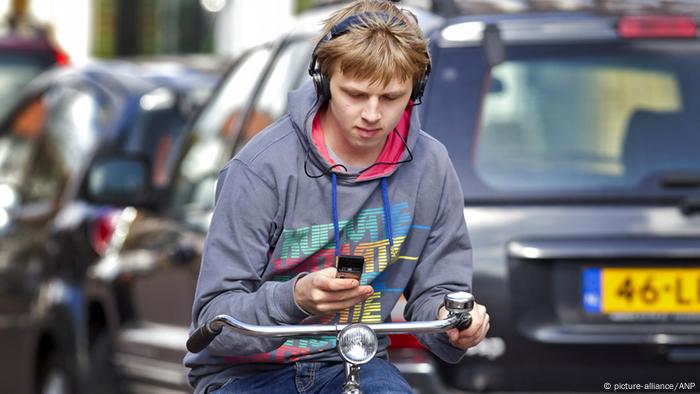 Radfahrer mit Handy und Kopfhörern im Straßenverkehr