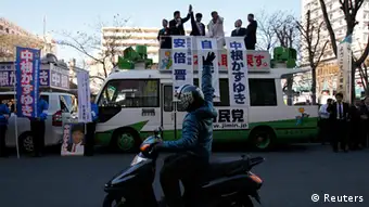 A man riding a motorbike waves to Japan's main opposition Liberal Democratic Party's (LDP) leader and former Prime Minister Shinzo Abe (3rd R atop truck) during a campaign for December 16 lower house election in Ageo, north of Tokyo December 11, 2012. Abe's opposition LDP and its smaller ally are heading for a resounding victory in Sunday's election, winning more than 300 seats in parliament's 480-member lower house, media surveys showed on Tuesday. REUTERS/Shohei Miyano (JAPAN - Tags: POLITICS ELECTIONS)