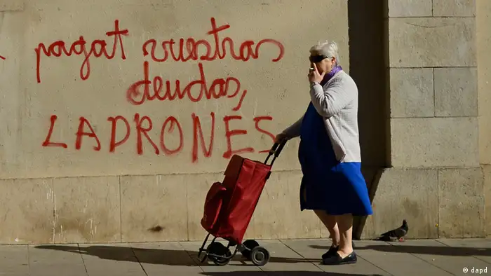 A women walks past graffiti reading Pay your debts thieves in Barcelona during the Spanish debt crisis 2012.