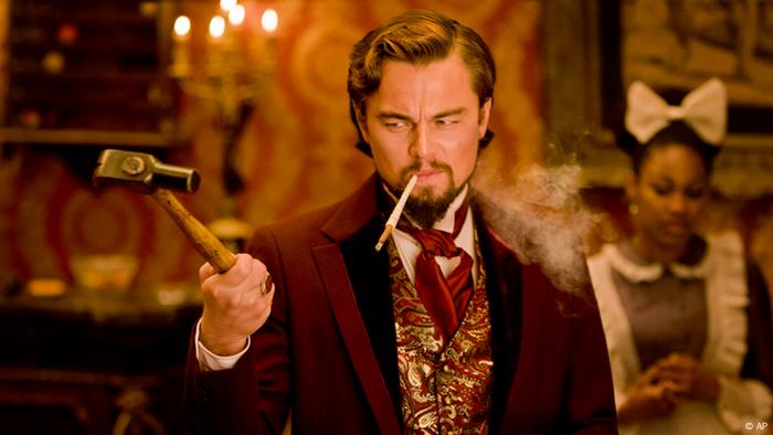 Leonardo DiCaprio hält einen Hammer in der Hand und raucht eine Zigarette in einer Filmszene von Django Unchained.