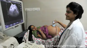 Dr. Nayna Patel (R), a pioneer of reproductive surrogacy in India, conducts an ultrasound on 30 year old surrogate mother - Rinku Macwan, bearing twin babies, at Kaival Hospital in Anand, some 90 kms from Ahmedabad, on October 31, 2011. Commercial surrogacy, made legal in India in 2002 and popular among foreign couples who are unable to conceive, has provided a large source of income for some Indian women acting as surrogate mothers despite local stigmas and ethical debates. The United Nations says that by its best estimates the seven billionth baby will be born somewhere on October 31, and countries around the world have planned events surrounding the demographic milestone. AFP PHOTO/Dibyangshu SARKAR (Photo credit should read SAM PANTHAKY/AFP/GettyImages)