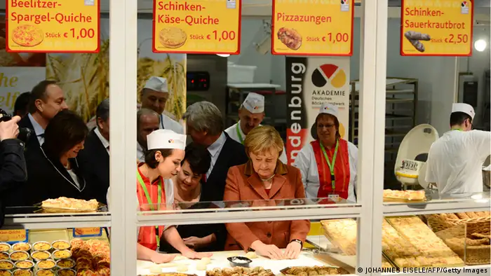 German Chancellor Angela Merkel (C) prepares a bread at the German bakery academy booth as she opens the Gruene Woche Agricultural Fair in Berlin on January 18, 2013. This year the official partner country of the fair is The Netherlands. AFP PHOTO / JOHANNES EISELE (Photo credit should read JOHANNES EISELE/AFP/Getty Images)