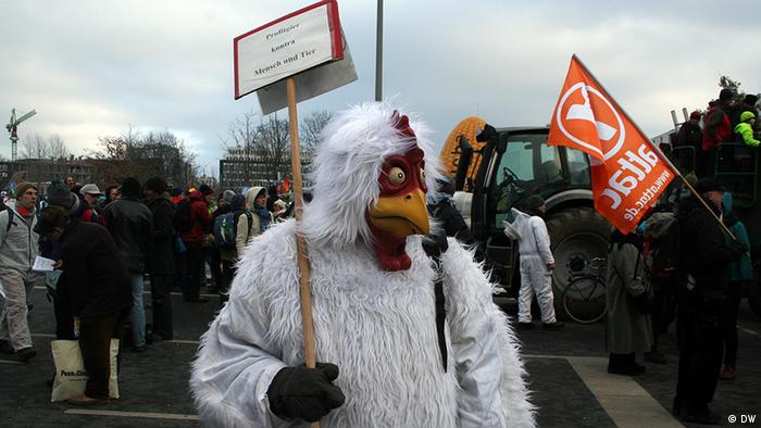 Ein als Huhn verkleideter Demonstrant hält ein Schild mit der Aufchrift 'Profitgier schlecht für Mensch und Tier' (Foto: DW)