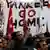 Protestors hold Turkish flags and a hand-painted sign that reads 'go home' (Photo: REUTERS/Umit Bektas)