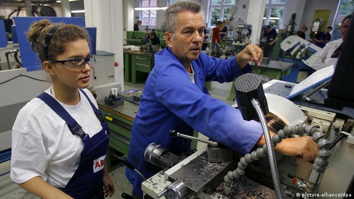 A man and a woman work on a machine in a factory