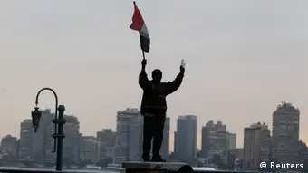 A protester opposing Egyptian President Mohamed Mursi stands on Kasr Elnile bridge holding the Egyptian flag during clashes with riot police along Qasr Al Nil bridge, which leads to Tahrir Square, in Cairo January 28, 2013. A man was shot dead on Monday in a fifth day of violence that has killed 50 Egyptians and prompted the Islamist president to declare a state of emergency in an attempt to end a wave of unrest sweeping the biggest Arab nation. REUTERS/Mohamed Abd El Ghany (EGYPT - Tags: POLITICS CIVIL UNREST)