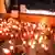 Мужчина сидит перед свечами, зажженными на тротуаре в память Арцу