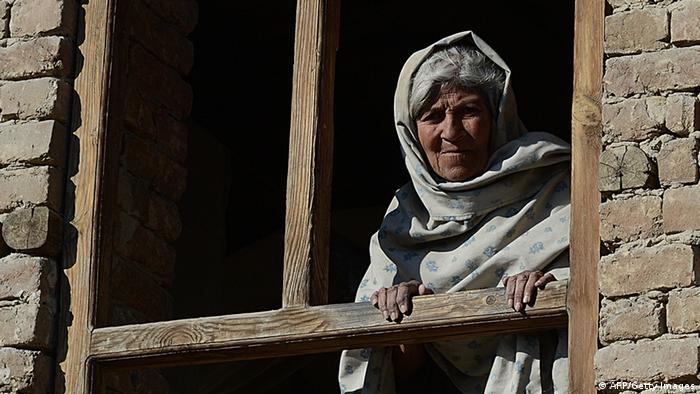 A elderly Afghan woman looks through the window of her house (Phtoto: AFP)