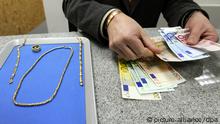 Pfandhausmitarbeiter Thomas Struck zahlt am Mittwoch (28.01.2009) in Hamburg einer Kundin Geld aus. Während viele Unternehmen unter der Finanzkrise leiden, könnte die Situation für Schmuck-Pfandleiher wie den Hamburger Thomas Struck kaum besser sein. Und das liegt vor allem an den historisch hohen Goldpreisen. Mit den steigenden Kursen des Edelmetalls sei auch der Wert des beliehenen Schmucks gestiegen. Foto: Maurizio Gambarini dpa/lno (zu dpa-Korr: Goldene Zeiten für Leihhäuser - Profitieren von hohen Goldpreisen vom 16.03.2009) +++(c) dpa - Bildfunk+++
