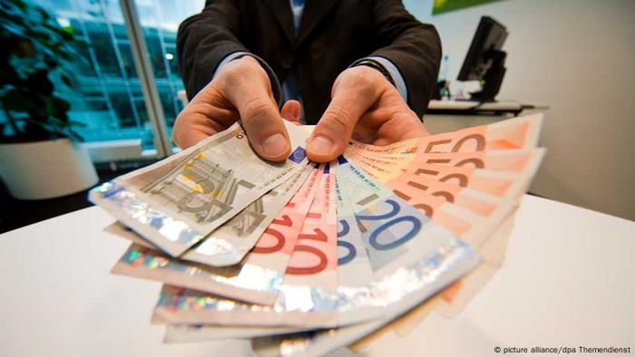Ein Mann hält einen Fächer aus Geldscheinen (Foto: picture alliance/dpa)