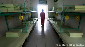 --FILE--A Chinese inmate walks past beds in a room at a female labor camp in Jurong city, east Chinas Jiangsu province, 6 March 2008. Meng Jianzhu, who became secretary of the Political and Legal Affairs Committee in November, said at a national law and order work conference that the re-education through labour, or laojiao, system would be halted after the move was rubber-stamped by the National Peoples Congress in March. The remarks were first reported by the bureau chief of the Legal Daily, the Justice Ministrys official mouthpiece, and were picked up by state media outlets. An official who attended the event confirmed Mengs comments. But state media sent mixed signals about the policy. A Xinhua report on the conference said only that authorities had pledged to reform the system, and some analysts noted that Meng spoke of halting rather than abolishing the laojiao system. pixel