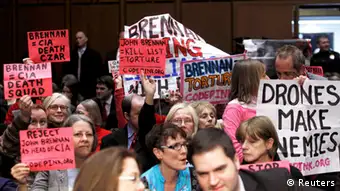Protesters hold signs as Deputy National Security Adviser John Brennan testfies before the Senate Intelligence Committee on his nomination to be the director of the CIA on Capitol Hill in Washington February 7, 2013. REUTERS/Gary Cameron (UNITED STATES - Tags: POLITICS)