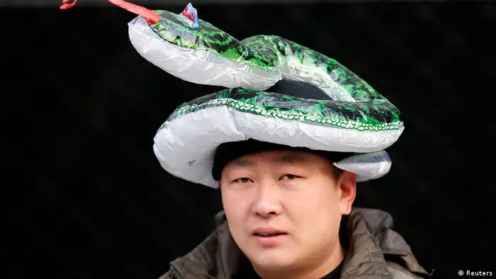 A shop owner wears a snake-shaped ballon on his head in order to attract customers during the temple fair in Ditan Park, also known as the Temple of Earth, in Beijing February 9, 2013. The Lunar New Year, or Spring Festival, begins on February 10 and marks the start of the Year of the Snake, according to the Chinese zodiac. REUTERS/Kim Kyung-Hoon (CHINA - Tags: ANNIVERSARY)