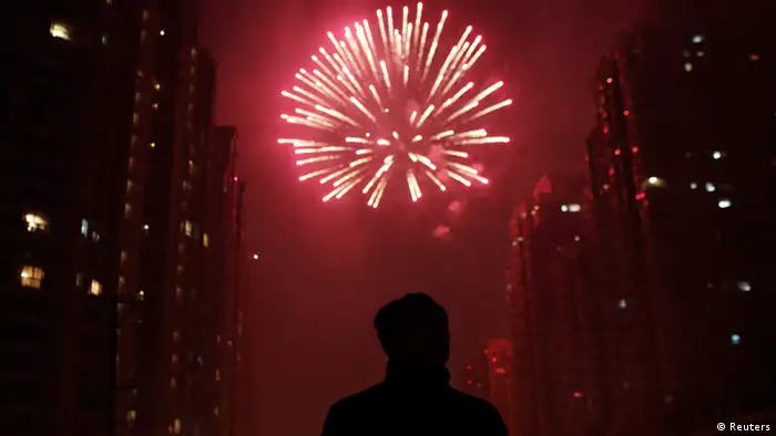 A man watches as fireworks light up the skyline of Shanghai in celebration of Chinese New Year in Shanghai early February 10, 2013. The Lunar New Year, or Spring Festival, begins on February 10 and marks the start of the Year of the Snake, according to the Chinese zodiac. REUTERS/Carlos Barria (CHINA - Tags: SOCIETY)