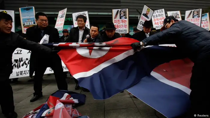 Activists from an anti-North Korea civic group try to tear a North Korea flag during a rally against North Korea's nuclear test near the U.S. embassy in central Seoul February 12, 2013. North Korea conducted its third nuclear test on Tuesday in defiance of U.N. resolutions, angering the United States and Japan and prompting its only major ally, China, to call for calm. REUTERS/Kim Hong-Ji (SOUTH KOREA - Tags: CIVIL UNREST POLITICS)