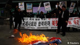 Activists from an anti-North Korea civic group burn a North Korea flag in front of banners bearing anti-North Korea messages near the U.S. embassy in central Seoul February 12, 2013. North Korea conducted its third-ever nuclear test on Tuesday, a move likely to anger its main ally China and increase international action against Pyongyang and its new young leader, Kim Jong-un. U.N. Secretary-General Ban Ki-moon condemned North Korea's test, saying it was a clear and grave violation of U.N. Security Council resolutions. The banner in the background reads, Cease nuclear test and cooperate with the international powers!� REUTERS/Kim Hong-Ji (SOUTH KOREA - Tags: CIVIL UNREST POLITICS TPX IMAGES OF THE DAY)