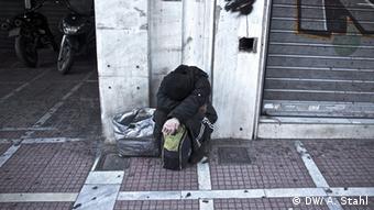 Ein obdachloser Mann sitzt auf einer Straße mit gesenktem Kopf