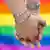 Two males holding hands in front of a rainbow flag