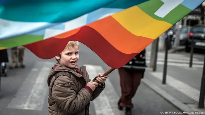 A person holds a placard reading Equality for all children .... as a boy waves a rainbow flag during a demonstration to support gay marriage and adoption on January 26, 2013 in Lyon, central France. French government plans to put the proposed legislation to parliament on January 29. AFP PHOTO / JEFF PACHOUD (Photo credit should read JEFF PACHOUD/AFP/Getty Images)