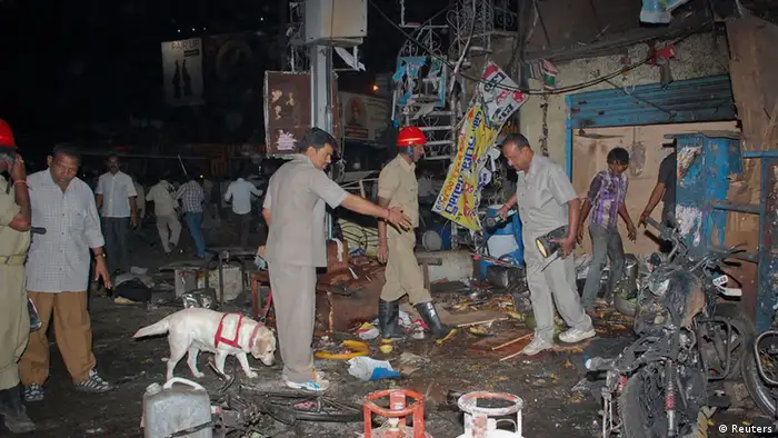Investigating officers use a sniffer dog as they inspect the site of an explosion at Dilsukh Nagar, in the southern Indian city of Hyderabad February 21, 2013. Two bombs placed on bicycles exploded in a crowded market-place in Hyderabad on Thursday, and the federal home minister said at least 11 people were killed and 50 wounded. REUTERS/Stringer (INDIA - Tags: CIVIL UNREST DISASTER ANIMALS)