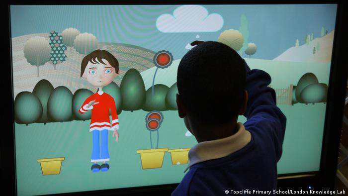 A child presses a touchscreen with the character Andy