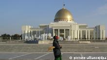 Eine Straßenkehrerin, die sich mit einem Tuch vor dem Mund gegen Wüstenstaub schützt, steht vor dem Präsidentenpalast in der turkmenischen Hauptstadt Aschchabad (Foto vom November 2005). In der einzigen Präsidentenwahl des unabhängigen Turkmenistan ließ sich Turkmenbaschi, der mit bürgerlichem Namen Saparmurat Nijasow heißt, 1992 mit fabelhaften 99,5 Prozent als Staatsführer bestätigen und sich später gar auf Lebenszeit ernennen. Die Republik Turkmenistan zählt zu den Ländern mit den größten Gas- und Ölvorkommen weltweit. Foto: Sebastian Fuchs (zu dpa Reportage: Im stalinistischen Disneyland: Leben unter dem Diktator Turkmenbaschi vom 27.12.2005) +++(c) dpa - Report+++
