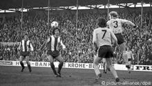 A Dortmund player heads away the ball as Gerd Müller looks on. 