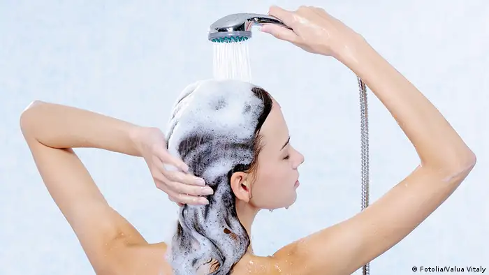 Eine junge Frau wäscht sich unter der Dusche die Haare