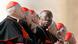 Amongst elderly, caucasian men wearing black robes and white caps, a man of African descent leans forward and peers right at the camera. (Photo: REUTERS/Alessandro Bianchi) Amongst elderly, caucasian men wearing black robes and white caps, a man of African descent leans forward and peers right at the camera. (Photo: REUTERS/Alessandro Bianchi)