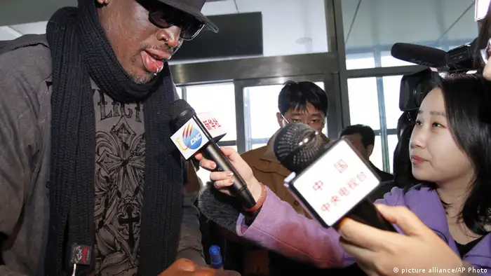 Former NBA star Dennis Rodman, left, speaks to the media at the airport in Pyongyang, before he leaves North Korea Friday, March 1, 2013. Rodman hung out with North Korea's Kim Jong Un during his improbable journey to Pyongyang, watching the Harlem Globetrotters with the leader and later drinking and dining on sushi with him.(AP Photo/Kim Kwang Hyon)