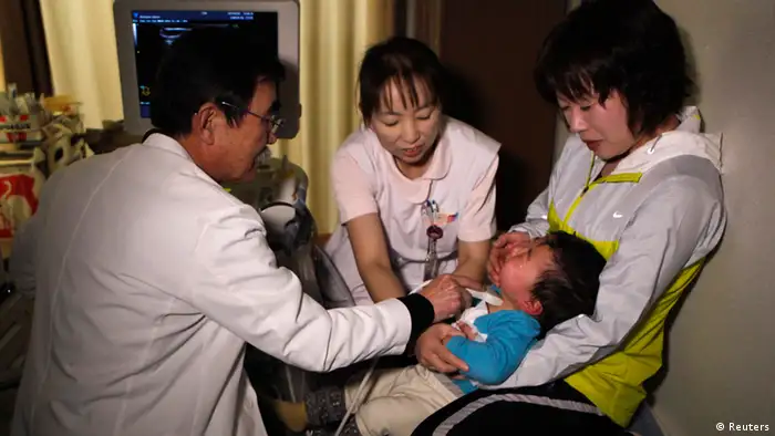 A doctor at a clinic in temporary housing complex Shunji Sekine (L) conducts a thyroid examination on a child in Nihonmatsu, about 50 km (31 miles) from the tsunami-crippled Fukushima Daiichi nuclear power plant, Fukushima prefecture February 25, 2013, ahead of the second-year anniversary of the March 11, 2011 earthquake and tsunami. As the World Health Organisation (WHO) says children in Fukushima may have a higher risk of developing thyroid cancer after the Daiichi nuclear disaster two years ago, mothers in Fukushima worry that local health authorities are not doing enough. Picture taken February 25, 2013. REUTERS/Chris Meyers (JAPAN - Tags: DISASTER HEALTH)