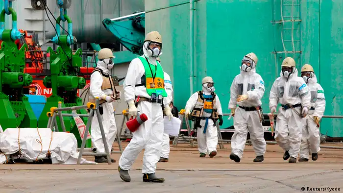 Workers walk near the TEPCO tsunami-crippled Fukushima Daiichi nuclear power plant