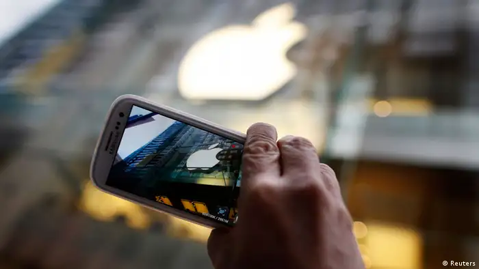 A passerby photographs an Apple store logo with his Samsung Galaxy phone in central Sydney in this September 21, 2012, file photo. Apple Inc lost a major ruling in its ongoing patent battle with Samsung Electronics on March 1, 2013, as a federal judge threw out part of a jury's $1.05 billion damages award against Samsung over a variety of phone products. REUTERS/Tim Wimborne/Files (AUSTRALIA - Tags: BUSINESS TELECOMS SCIENCE TECHNOLOGY)