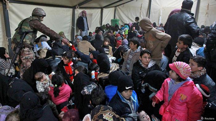 Ein jordanischer Soldat verteilt Wasser und Nahrung an syrische Flüchtlinge, die die Grenze nach Jordanien passiert haben. (Bild: REUTERS/Muhammad Hamed)