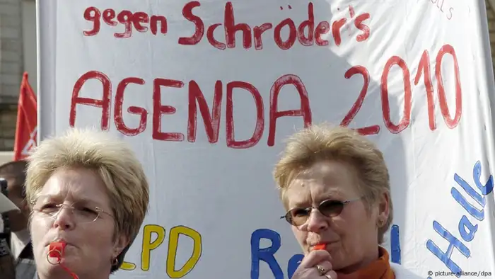 Mit Trillerpfeifen und einem Plakat gegen Schröders Agenda 2010 demonstrieren Mitarbeiter des von der Schließung bedrohten Bombardier-Werkes Waggonbau Halle-Ammendorf am 19.03.2004 in Halle (Saale) für den Erhalt des Produktionsstandortes, Foto: Peter Endig/dpa