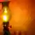 A lit kerosene lamp stands by the wall