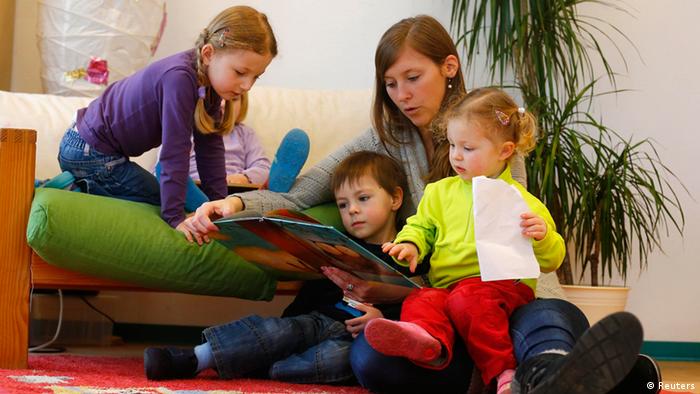 Kindergarten in Hanau - Drei Kinder schauen sich zusammen mit einer Betreuerin ein Buch an - Foto:Kai Pfaffenbach