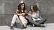 Two sitting girls are looking at their smartphones