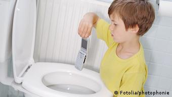 Ein Junge hält ein Mobiltelefon über eine Toilettenschüssel, um es hineinzuwerfen