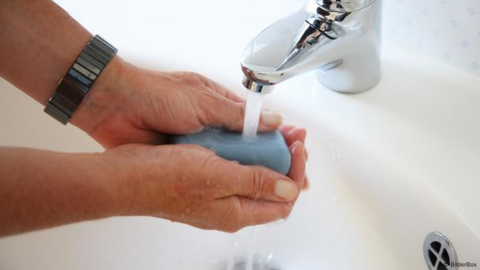 Person washing hands under water tap with soap