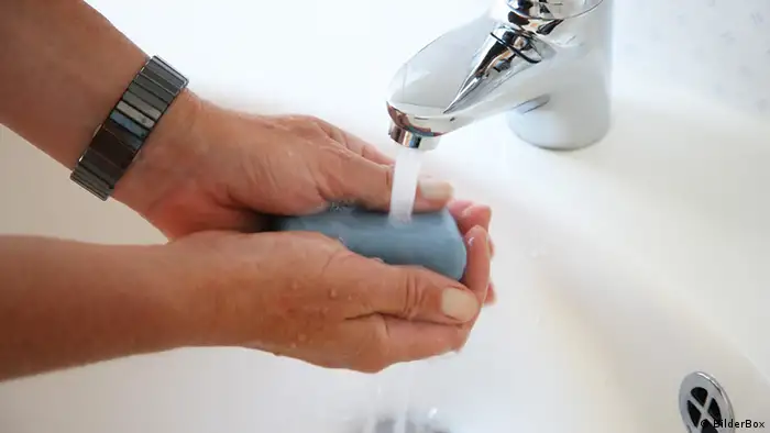 Person washing hands under water tap with soap