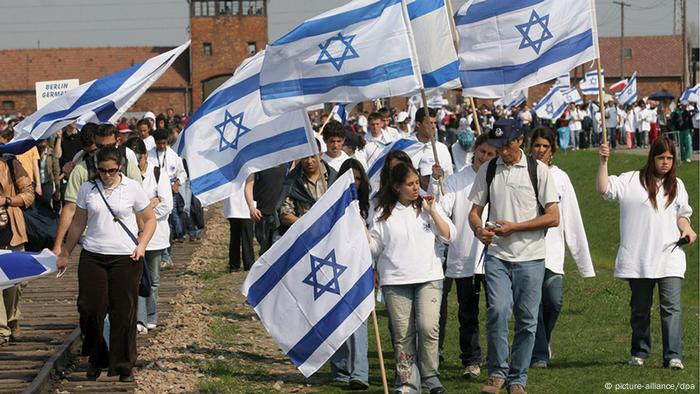 Menschen mit israelischen Fahnen vor der Gedenkstätte Auschwitz.
