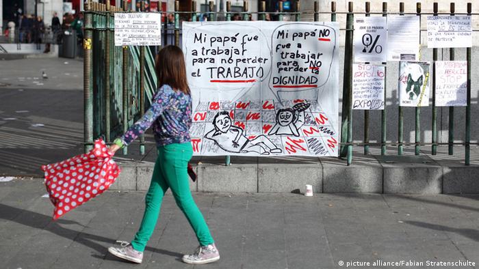 A woman walks past a banner protesting against unemployment policies (photo: Fabian Stratenschulte pixel)