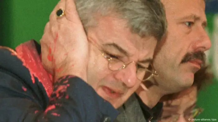 Von einem Farbbeutel getroffen faßt sich Bundesaußenminister Joschka Fischer erschrocken an sein rechtes Ohr. Der Farbbeutel wurde am Donnerstag (13.05.1999) während des Bündnis 90/Die Grünen-Sonderparteitages über den Kosovo-Krieg in Bielefeld von einem Mann auf Fischer geworfen. (Bild: dpa )