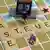 Eine Miniaturfigur trägt zwei Geldkoffer auf einem Scrabble-Spiel in eine Bank (Foto: dpa)