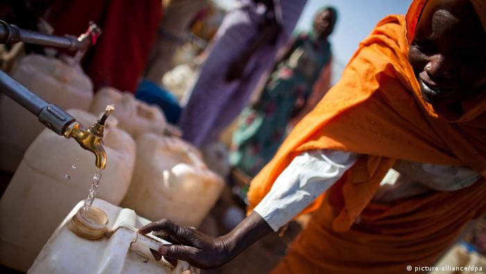 Eine Frau in Darfur füllt Wasserbehälter auf