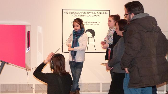 Ein Mädchen hört in einem Museum etwas zum Holocaust
