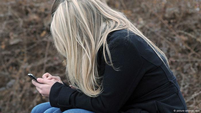 Mädchen auf einer Parkbank mit Handy (Foto: Armin Weigel/dpa)