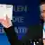 Лидер партии "Альтернатива для Германии" Бернд Луке показывает на учредительном съезде бюллетень для голосования
